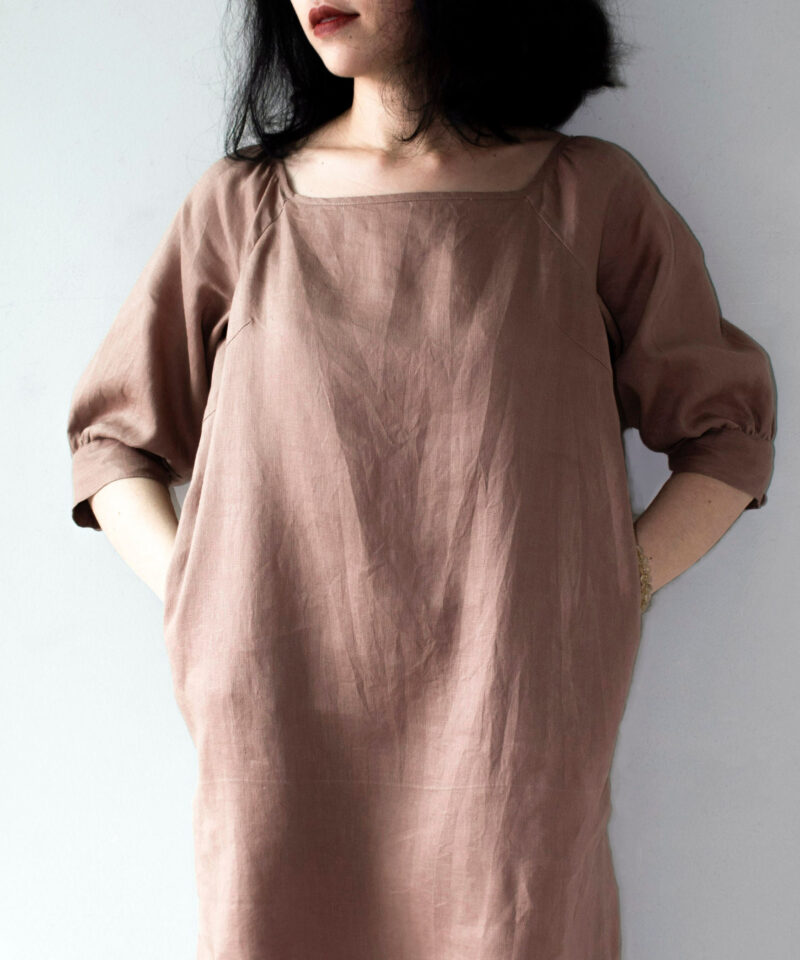 Crafted from breathable 100% linen, this earthy brown dress features a square neckline and raglan sleeves, creating a naturally elegant silhouette. The mid-length cut offers a timeless charm, while the relaxed fit gently flows with your body for effortless summer comfort. A simple yet refined piece for lovers of minimalist fashion.