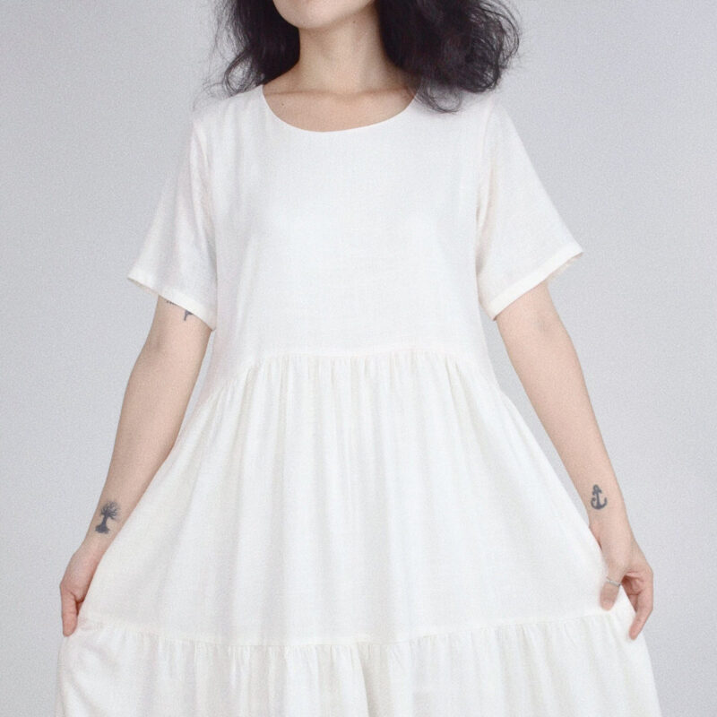 Crafted from 100% natural linen, this pure white dress features a soft tiered silhouette that flows effortlessly with every movement. The round neckline and short sleeves enhance its minimalist charm, making it perfect for warm-weather days or a slow-living, nature-inspired wardrobe.