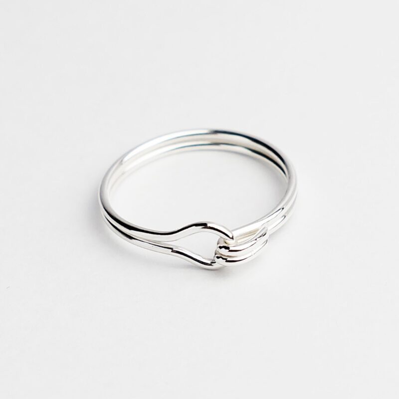 A delicate lover knot ring handcrafted in 925 sterling silver, featuring a double-wire loop that intertwines into a soft, symbolic knot. Its minimalist form evokes unity and emotional connection, making it a timeless piece for everyday wear or as a thoughtful gift. The high-polish finish highlights the elegance of silver and the artisanal quality of the craftsmanship.