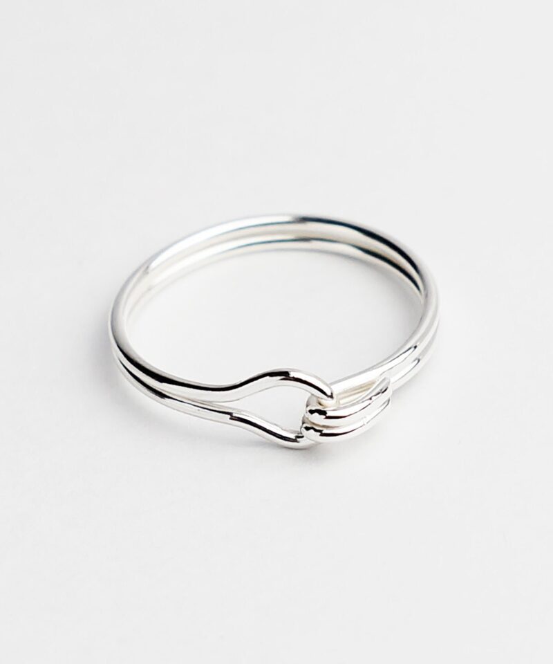 A delicate lover knot ring handcrafted in 925 sterling silver, featuring a double-wire loop that intertwines into a soft, symbolic knot. Its minimalist form evokes unity and emotional connection, making it a timeless piece for everyday wear or as a thoughtful gift. The high-polish finish highlights the elegance of silver and the artisanal quality of the craftsmanship.