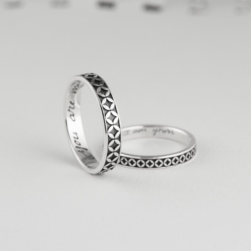 Close-up of two Japanese coin motif silver rings, positioned to reveal custom engraving inside reading "you are mine" and "I am yours." The oxidized black engravings create a striking contrast with the polished silver, offering a perfect balance of detail, love symbolism, and personalization.