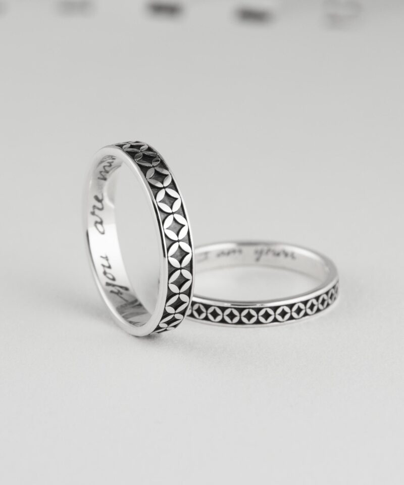Close-up of two Japanese coin motif silver rings, positioned to reveal custom engraving inside reading 