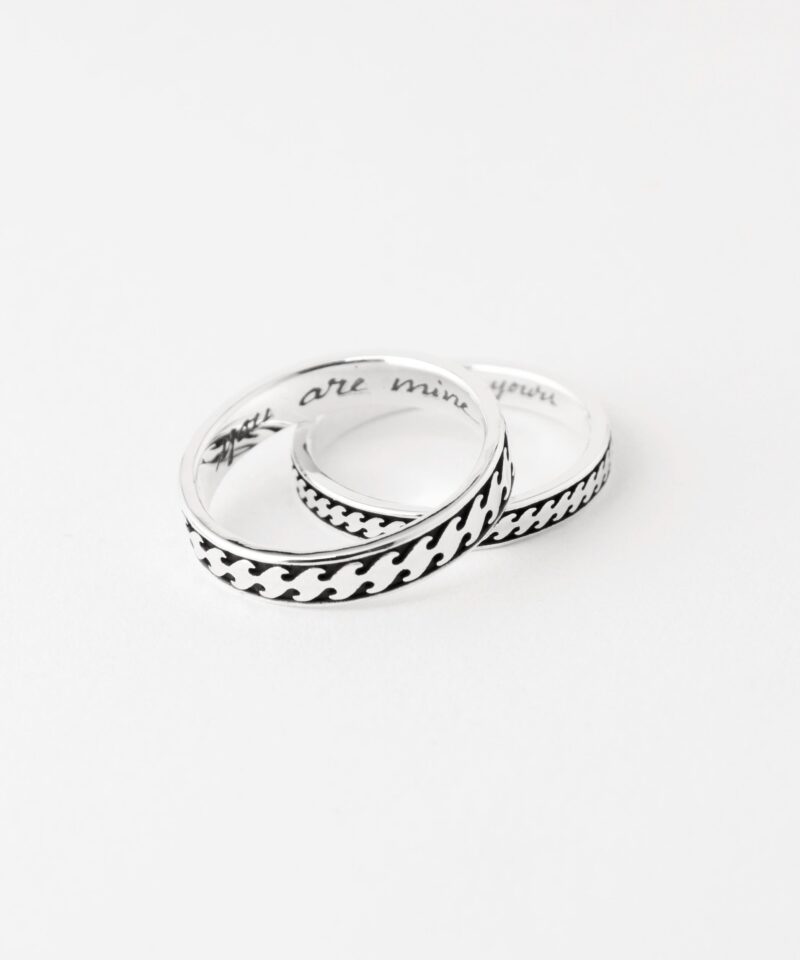 A romantic flat lay of two sterling silver Japanese wave rings resting together on a clean white background. The darkened engraving contrasts beautifully against the bright silver, highlighting the intricate movement of the wave pattern. Subtle inscriptions are visible inside the rings, offering a glimpse of personalized messages. This serene setup celebrates eternal love and the graceful flow of time shared between two hearts.
