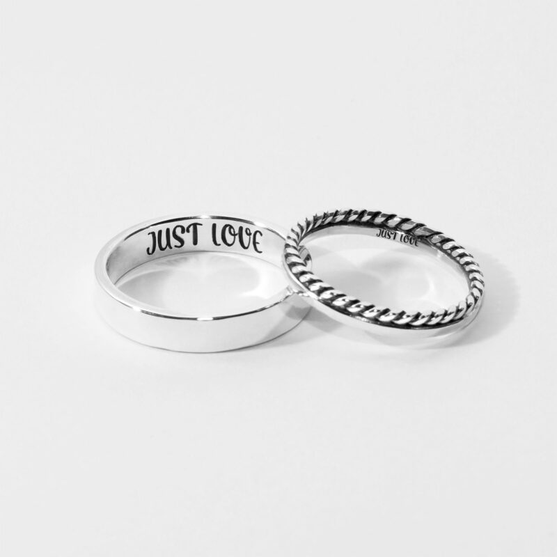 A beautiful set of two 925 sterling silver couple rings displayed on a white background. The thicker band has a simple polished finish with "JUST LOVE" engraved inside, while the thinner band features a charming twisted rope design. Both rings symbolize a timeless and meaningful connection between lovers, crafted with minimalist elegance for daily wear or special occasions.