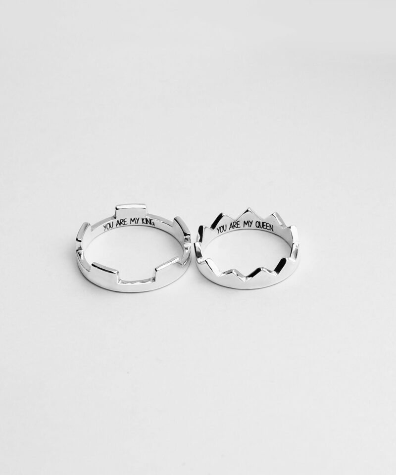 A pair of 925 sterling silver rings designed in the shape of royal crowns, one engraved with 