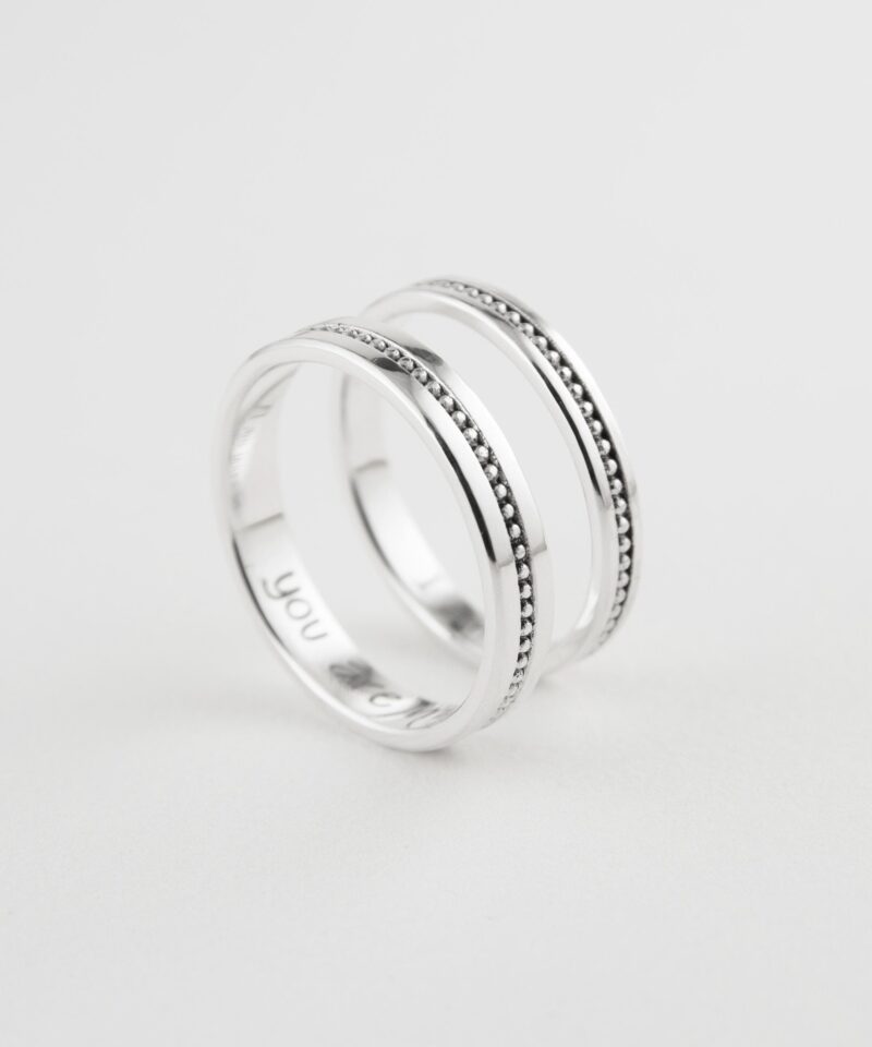 A lovely arrangement of two matching sterling silver rings standing side by side on a white background. The milgrain beaded details shimmer subtly under soft lighting, highlighting the craftsmanship and delicate texture of each band. These rings celebrate love through minimalist elegance, ideal for meaningful everyday moments.