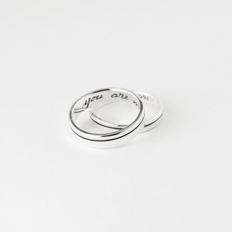 Product photography of a sterling silver ring with 'you are mine' custom engraving inside the band. The image displays the ring against a white background with a sample of the handwritten text above it for customization reference. Precise measurements show the ring is 4.5mm in width and 1.4mm in thickness. The polished silver band features a distinctive center groove design that runs around the exterior circumference, creating an elegant contemporary look.