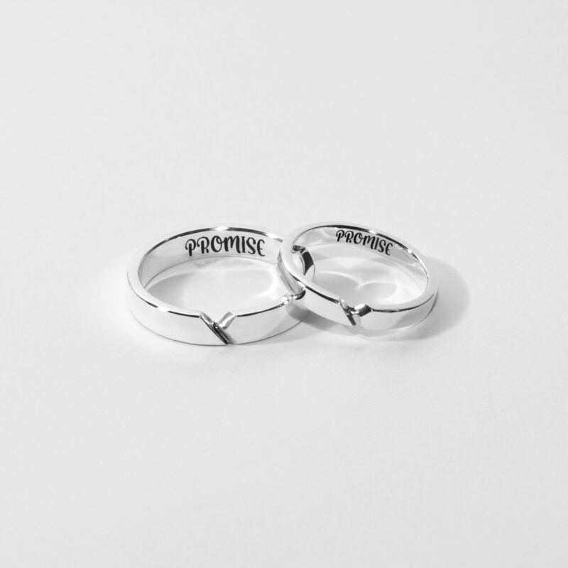 A pair of minimalist sterling silver couple rings with a subtle connection line design, engraved with the word "PROMISE" inside each band. These matching rings feature a clean, modern aesthetic with a symbolic groove detail that unites when placed together. Perfect for couples celebrating their commitment and love, the polished silver surface offers a timeless and elegant look. Displayed against a clean white background, highlighting the craftsmanship and emotional meaning of these promise rings