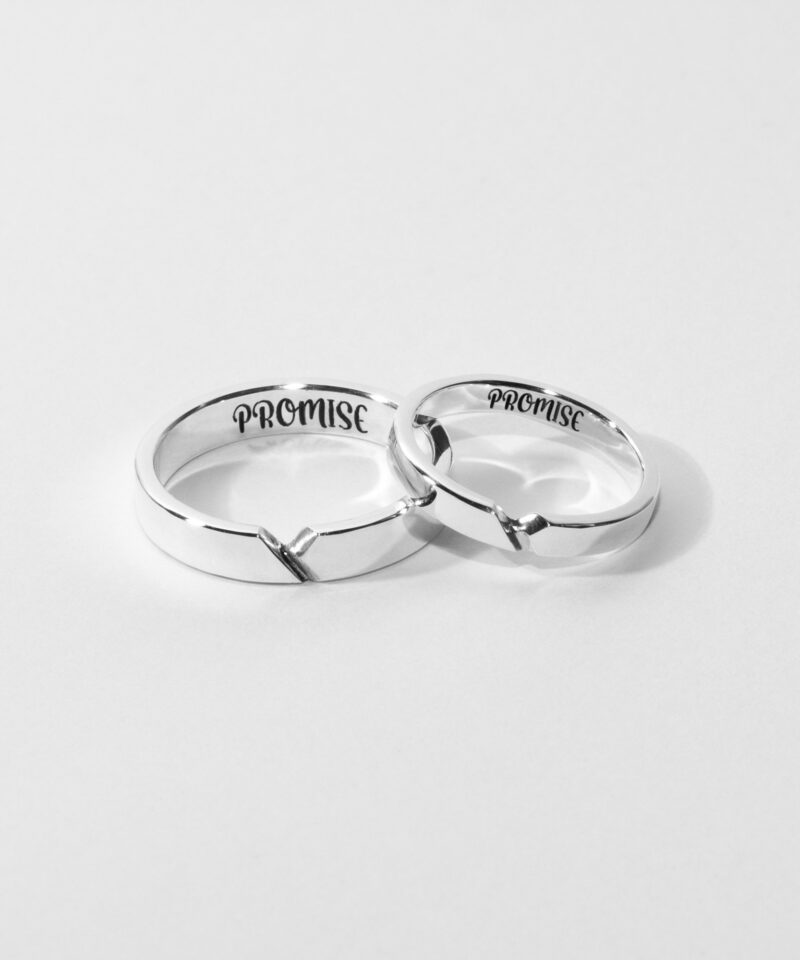 A pair of minimalist sterling silver couple rings with a subtle connection line design, engraved with the word 