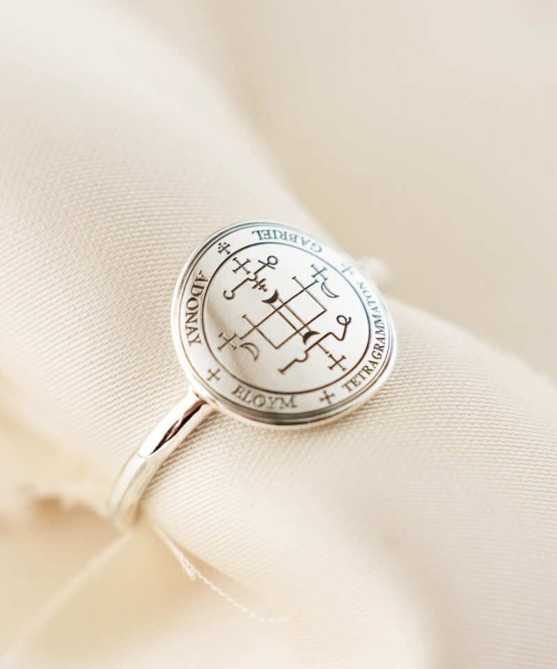 Elegant sterling silver ring with the Sigil of Archangel Gabriel resting on a beige cloth, showcasing its clean polished finish and mystical engraved symbol for spiritual clarity and divine protection.