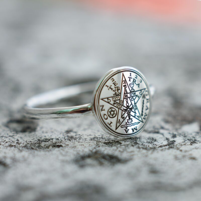 925 silver ring with the Tetragrammaton magical symbol centered on a polished round face, surrounded by Hebrew and alchemical inscriptions. Captured on a rough stone background, the photo showcases the deep engraving and spiritual craftsmanship.