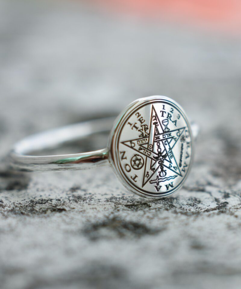 925 silver ring with the Tetragrammaton magical symbol centered on a polished round face, surrounded by Hebrew and alchemical inscriptions. Captured on a rough stone background, the photo showcases the deep engraving and spiritual craftsmanship.