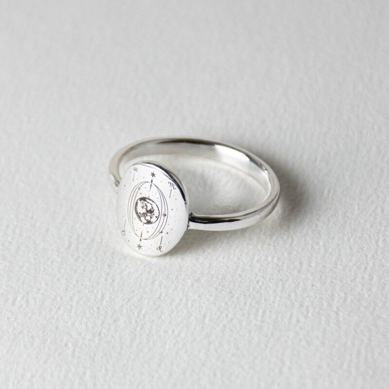 Minimalist 925 silver ring with a round face engraved with The World tarot card orbit, enhanced with a small white cubic zirconia stone in the center. The detailed constellation-inspired engraving includes planetary glyphs and radiating orbit lines, symbolizing the universe’s harmony and divine cycles. Perfect for spiritual seekers or cosmic jewelry collectors.