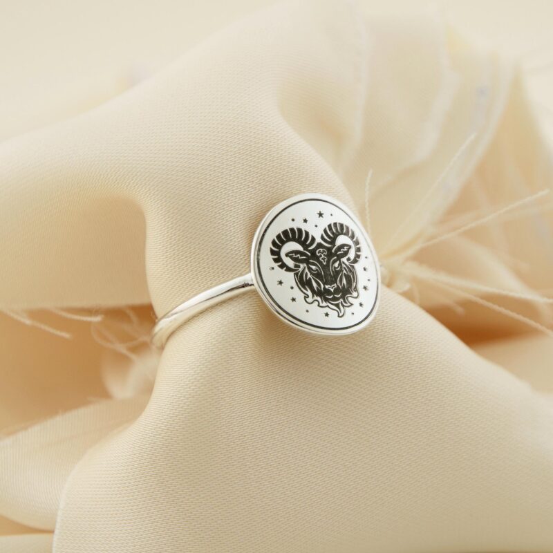 Close-up of the Aries zodiac silver ring, crafted from solid 925 sterling silver with a polished oval face engraved with a majestic ram and surrounding stars. Displayed on elegant cream-colored fabric, this astrology-inspired ring is ideal for personalized horoscope gifts or spiritual statement jewelry with symbolic meaning for Aries individuals.