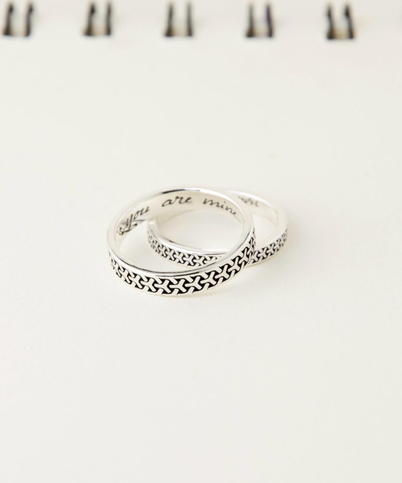 A close-up of two sterling silver couple rings featuring a Japanese geometric pattern. The rings are stacked together, highlighting the intricate oxidized texture and engraved inner band with “You are mine” and “I am yours”.